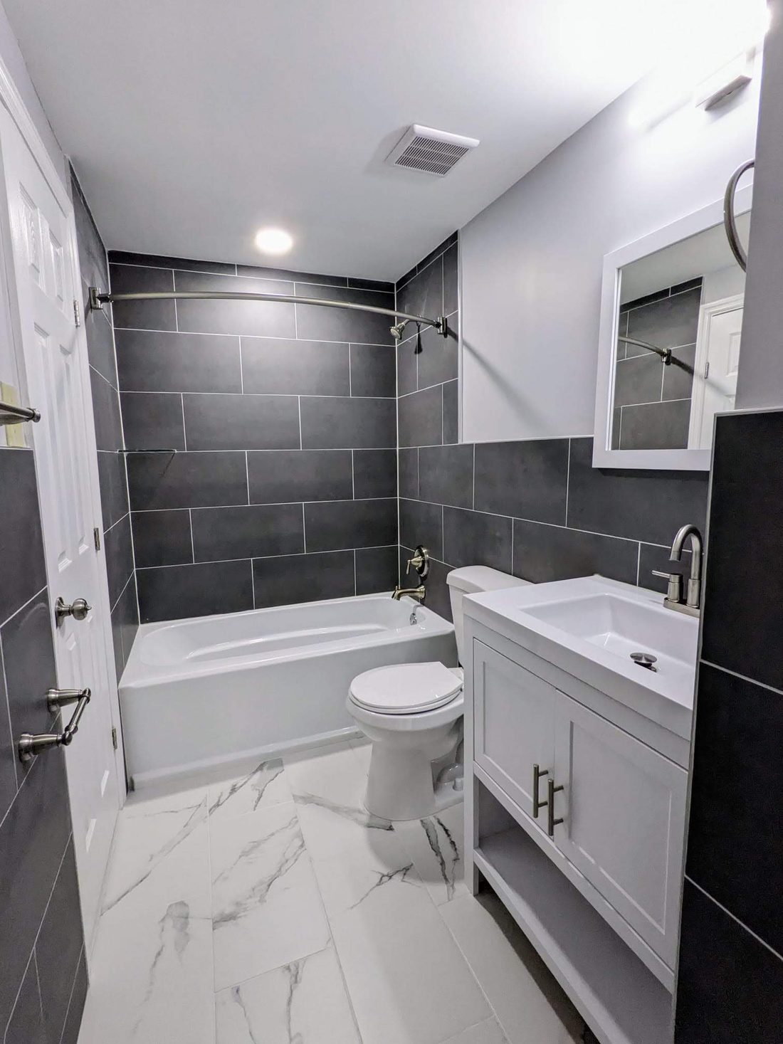 Bathroom with charcoal wall tile, a soaking tub and marble-look floor