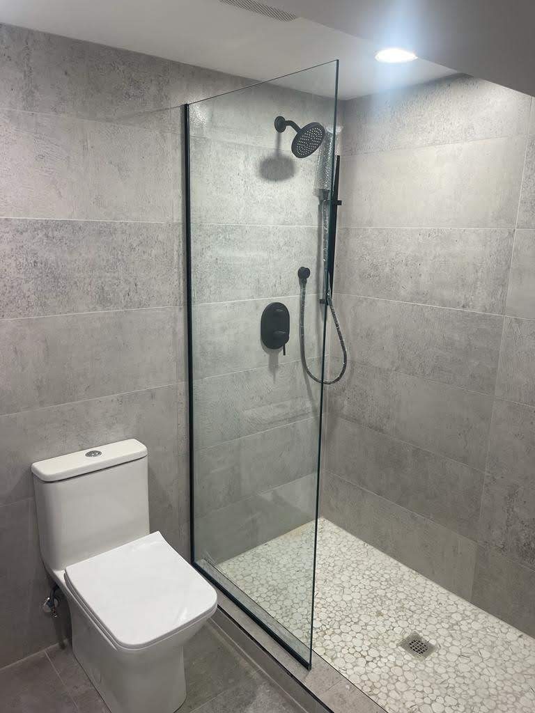 Walk-in shower with large-format tile, a pebble floor and matte black fixtures